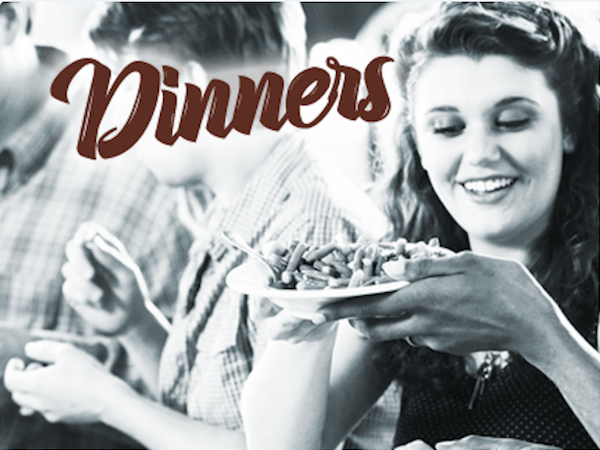 A woman smiling while holding a plate of food.