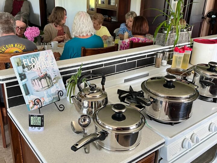 Stainless steel pots on stove, people dining